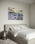 Peaceful Japandi style bedroom interior featuring a massive horizontal original painting by two sisters from Ukraine. The serene water lilies canvas in a silver frame hangs on a neutral plaster wall above a cozy grey textured upholstered bed.