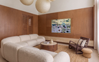 Oversized horizontal water lilies canvas painting styled in a warm organic modern living room. The large contemporary fine art piece hangs on a rich mid-century wooden paneled wall behind a premium cream white boucle sectional sofa. Complete with a round walnut coffee table and minimalist paper lantern pendant lights.